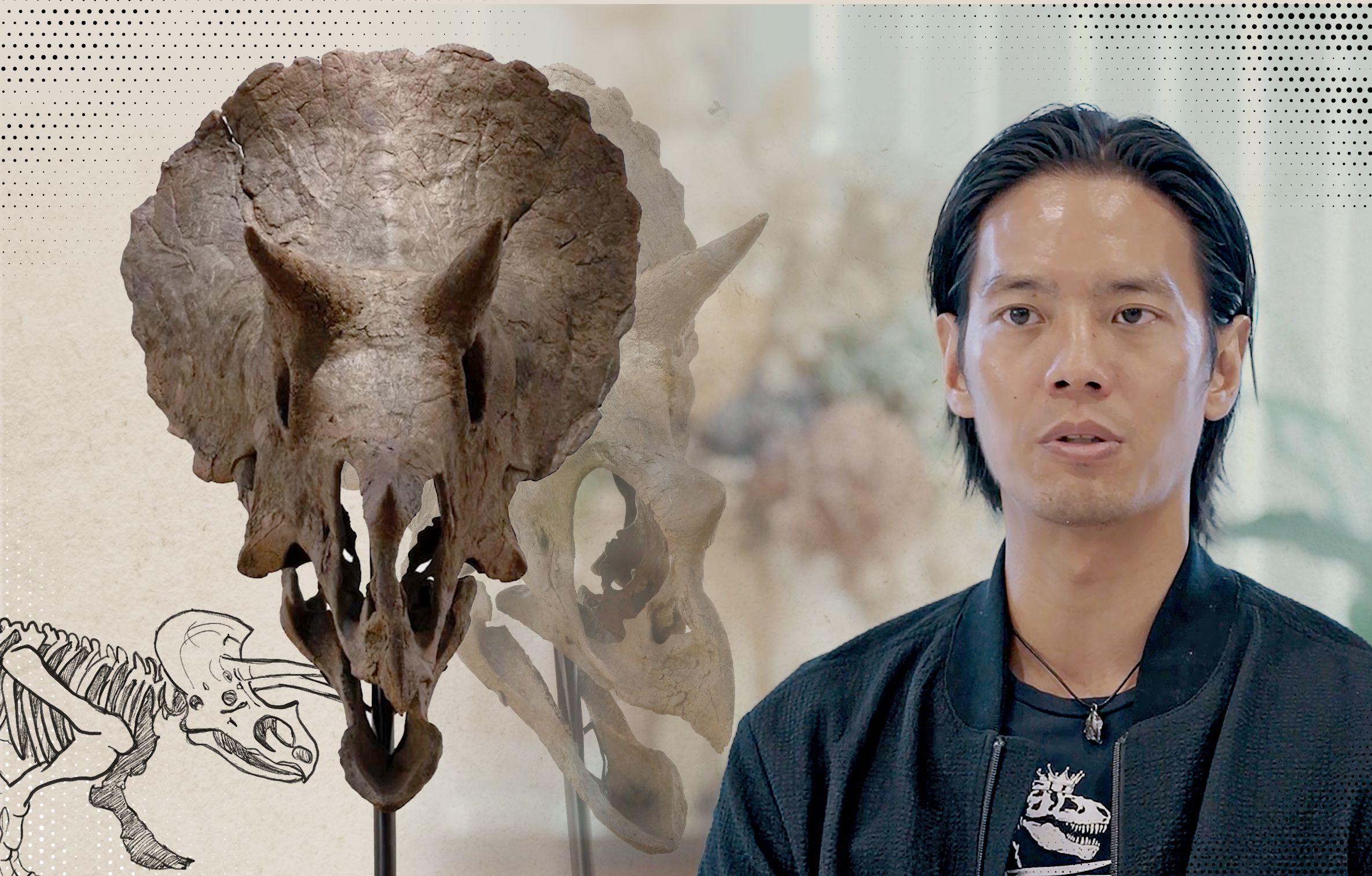 A man seated beside a dinosaur skeleton, gesturing as he speaks during an interview.