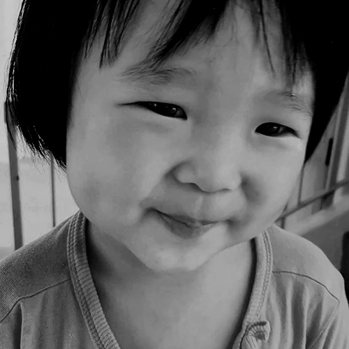 Black-and-white close-up of Megan Khung smiling softly at the camera.